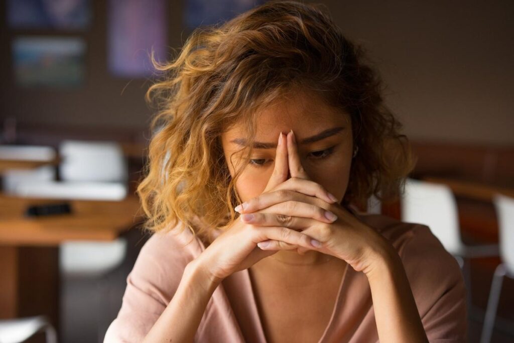 Pessoa exausta com as mãos na cabeça, representando cansaço emocional